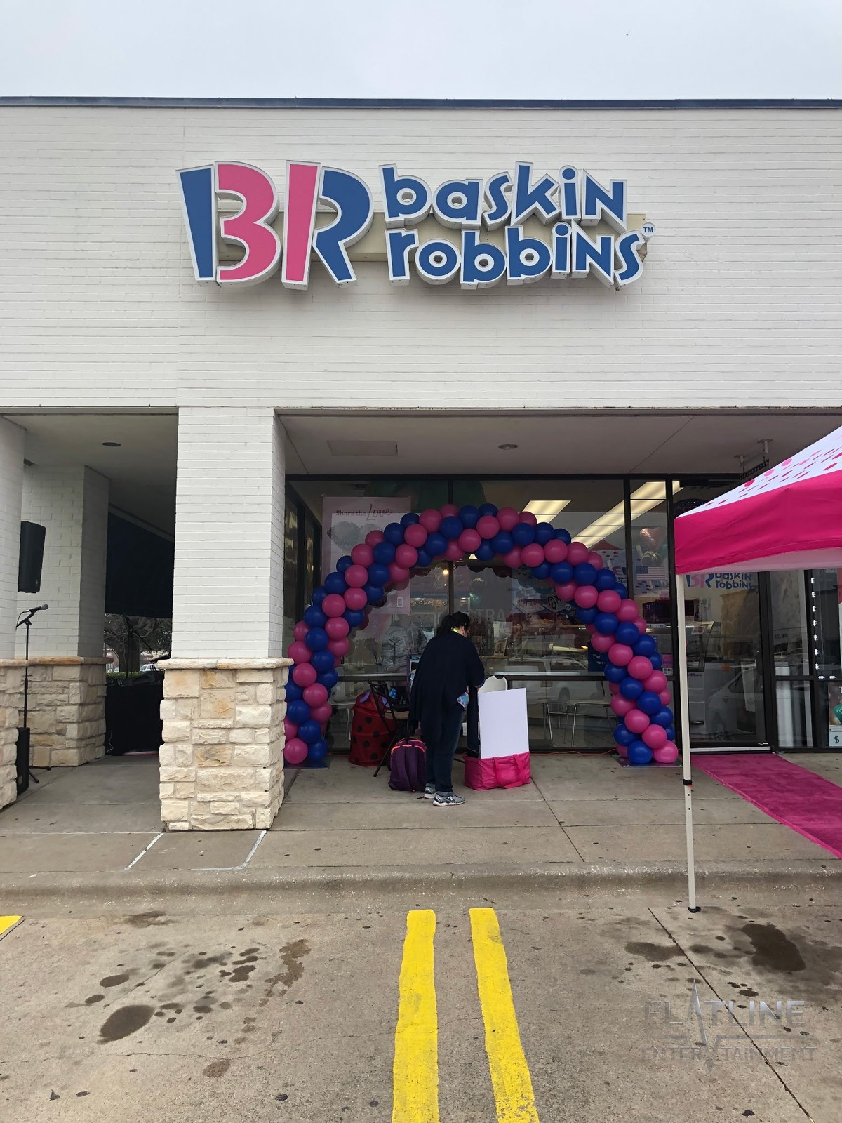 An outdoor corporate promo event at a Baskin Robbins storefront with a balloon arch and the Flatline sound setup