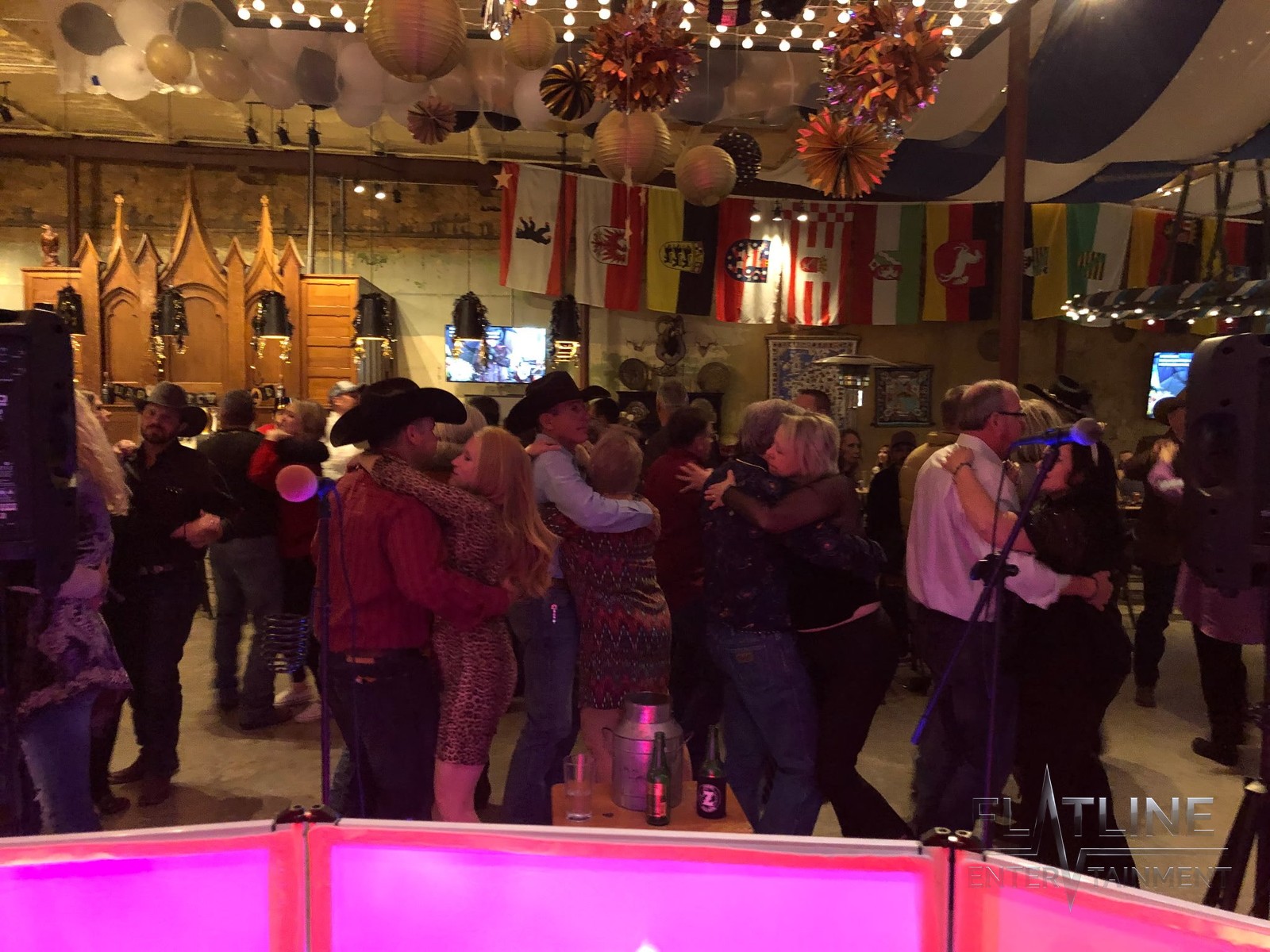 A packed dance floor with couples dancing in front of the DJ booth