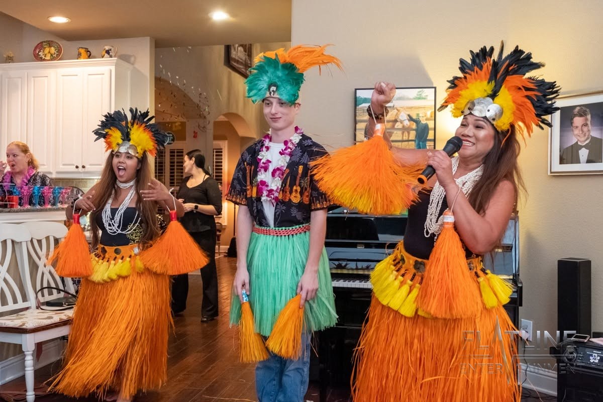Hula dancers in bright orange costumes posing at a birthday party