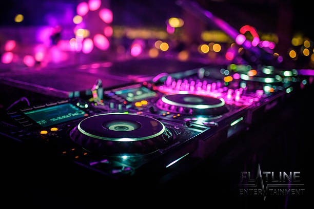 Close-up of DJ turntables and a mixer glowing under party lights