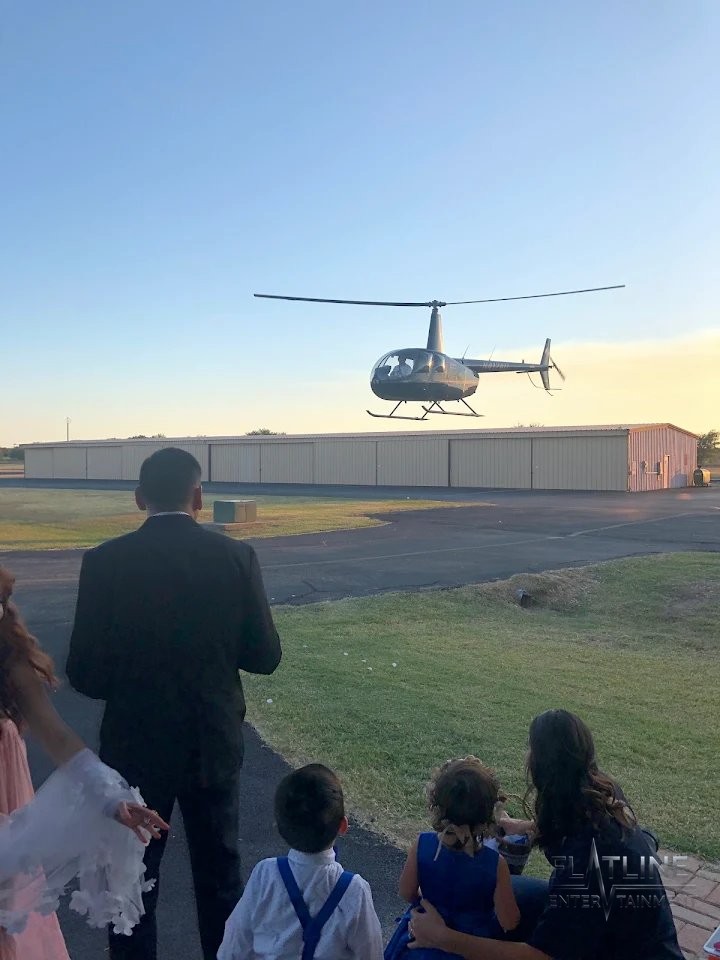 A helicopter arriving over the venue as wedding guests watch from below